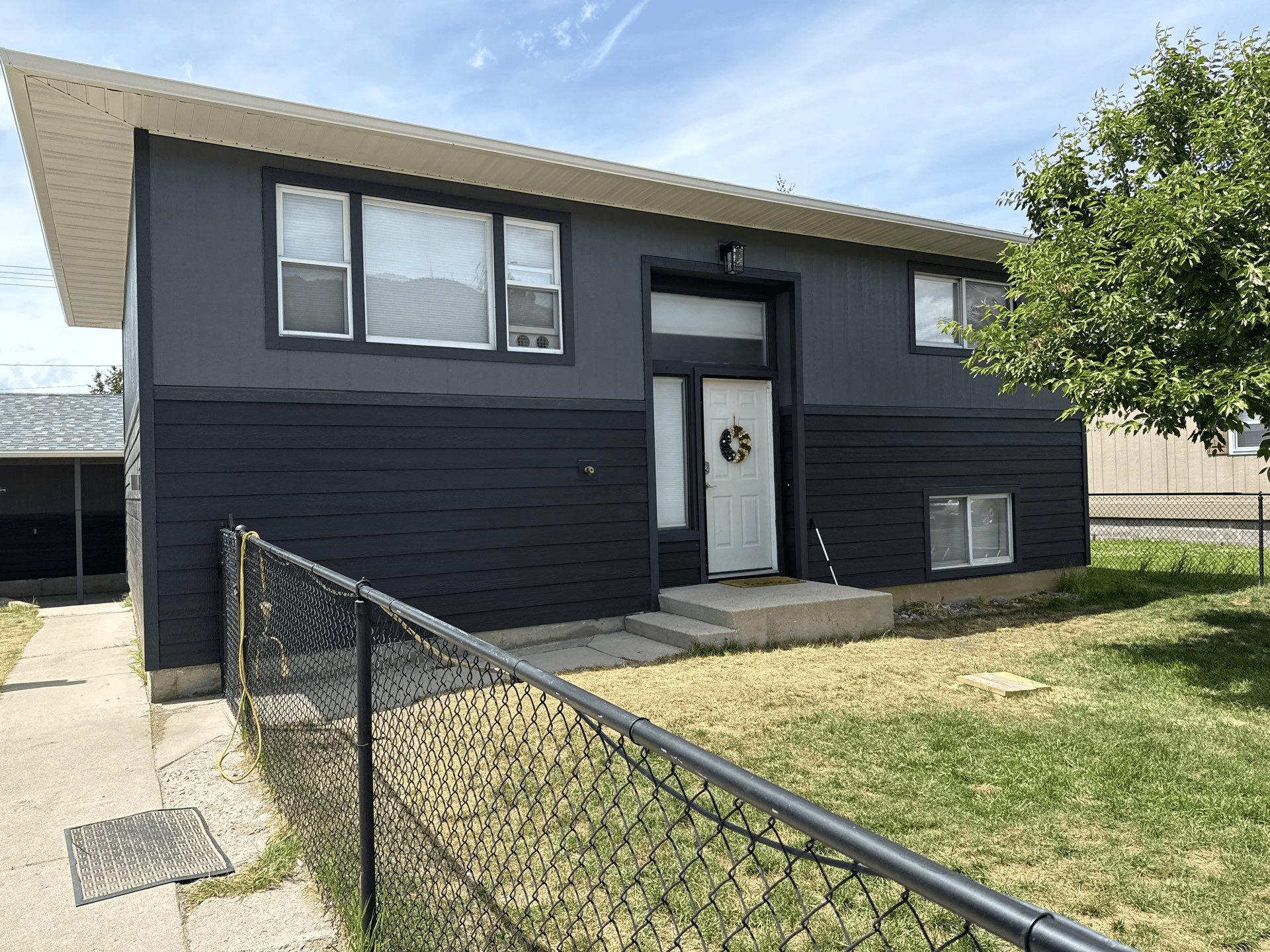 Modern black house exterior with well-maintained lawn and front steps.