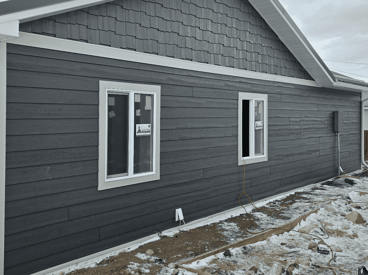 Exterior Home Siding New gray siding installation on residential house exterior with windows.