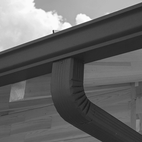 Close-up of a black rain gutter attached to a building's roof.