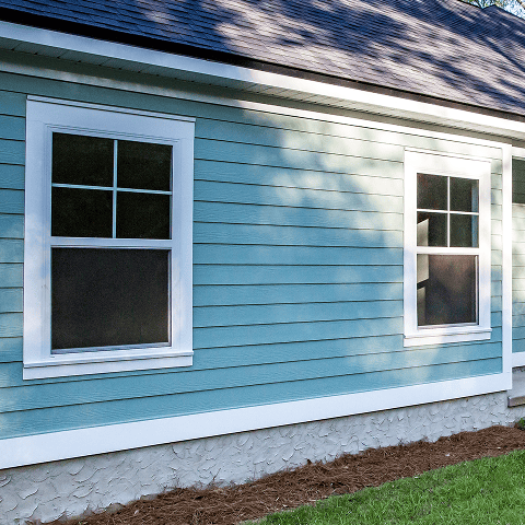 Bright blue house with new vinyl siding and white window frames.