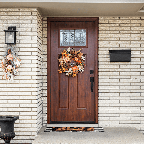 Beautiful wooden front door decorated with autumn wreath, enhancing curb appeal.