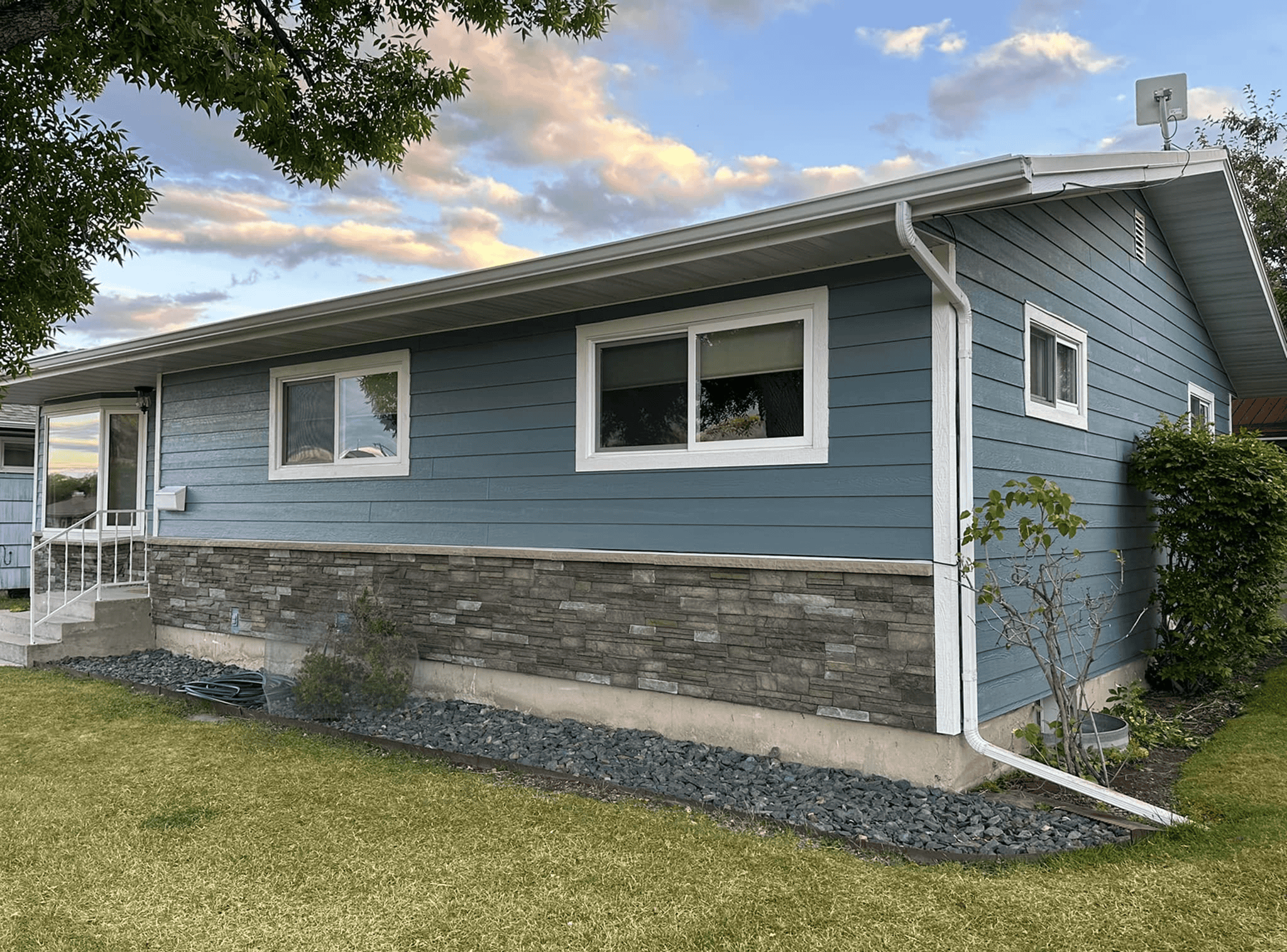 Modern blue house with stone accents and white trim, showcasing exterior renovation work.