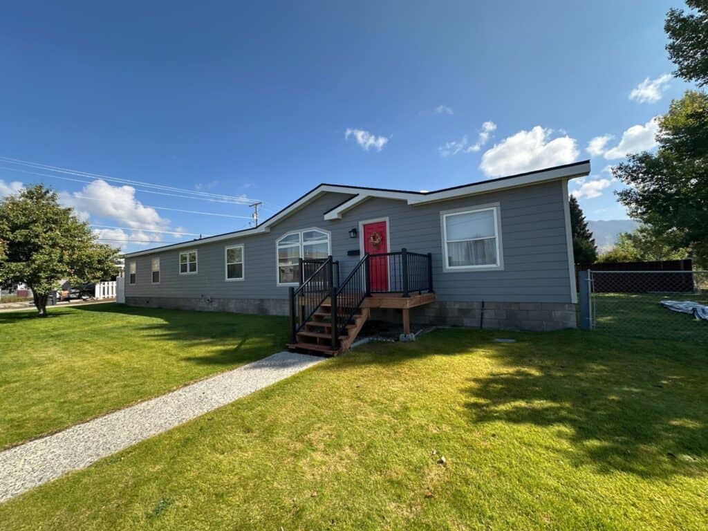 Modern blue house with red door and well-maintained lawn, showcasing quality exterior renovation.