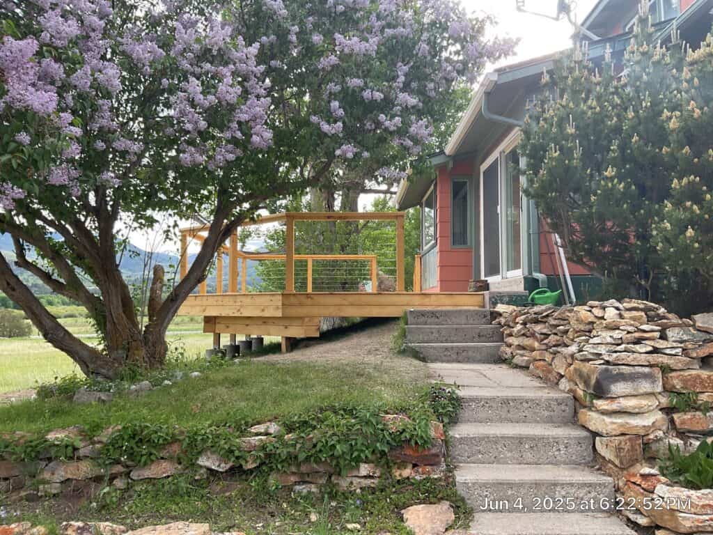 Deck Installation at Example Co Deck construction with wooden railing and steps in a residential yard.