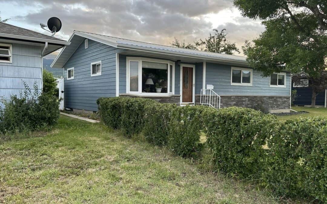 Modern blue house with well-maintained lawn and landscaping, showcasing quality home improvement wor.