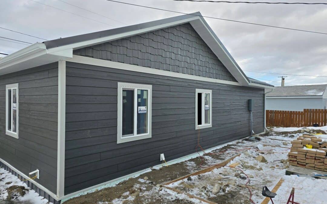 Exterior view of a newly renovated house with dark gray siding and white trim, showcasing modern con.