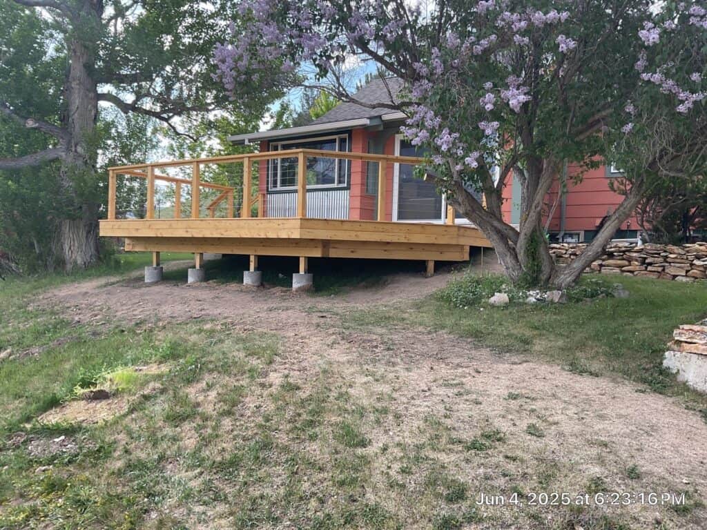 Deck Construction at Example Co Deck construction with wooden railing in a residential backyard.