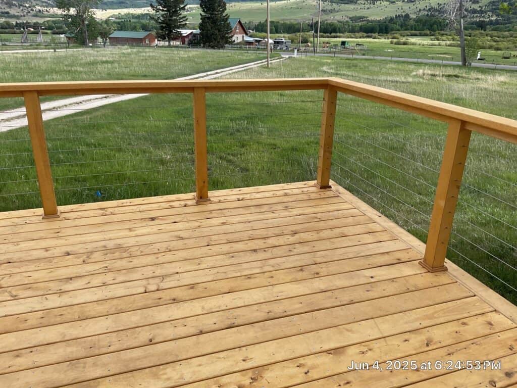 Wooden deck with railing in a rural setting Wooden deck with safety railing overlooking green fields and distant houses.