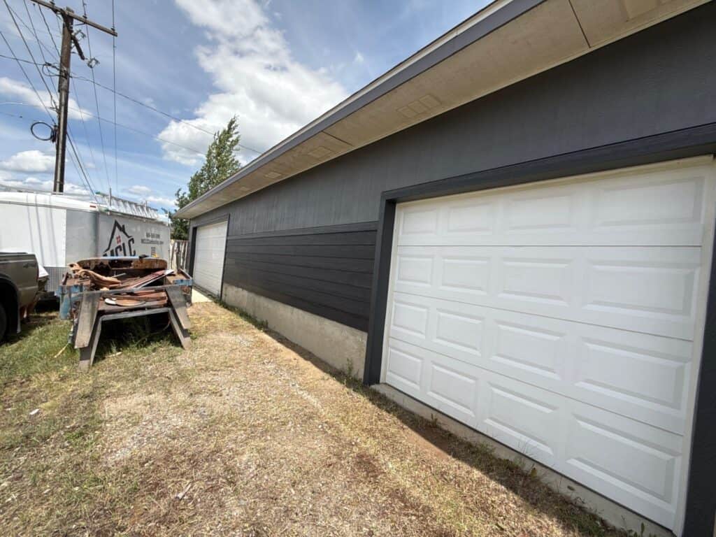 Garage with black siding and white door in a residential area.