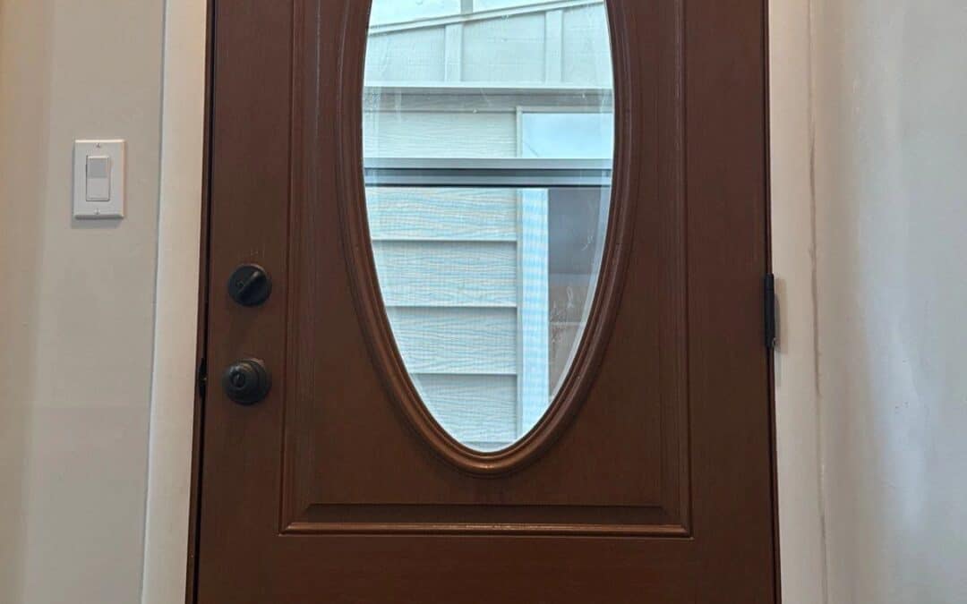 Wooden front door with oval glass window, installed at Example Co. home.