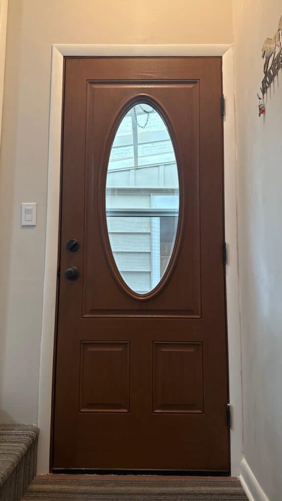 Front Door Installation Wooden front door with oval glass window, modern residential entryway.