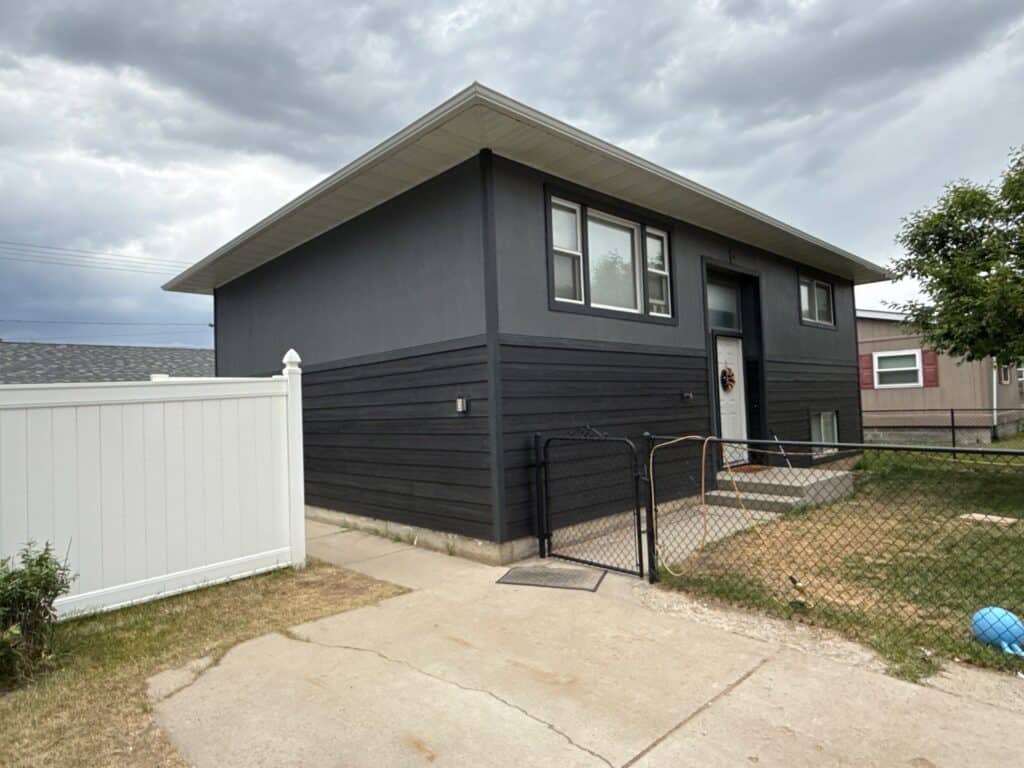 Black exterior home with a small front yard and accessible ramp.