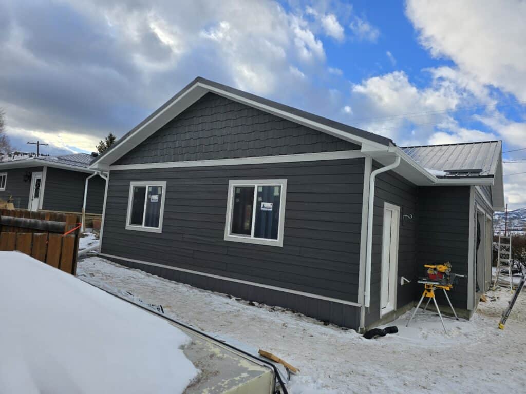 Modern Gray House Gray house with white trim and snow-covered yard.