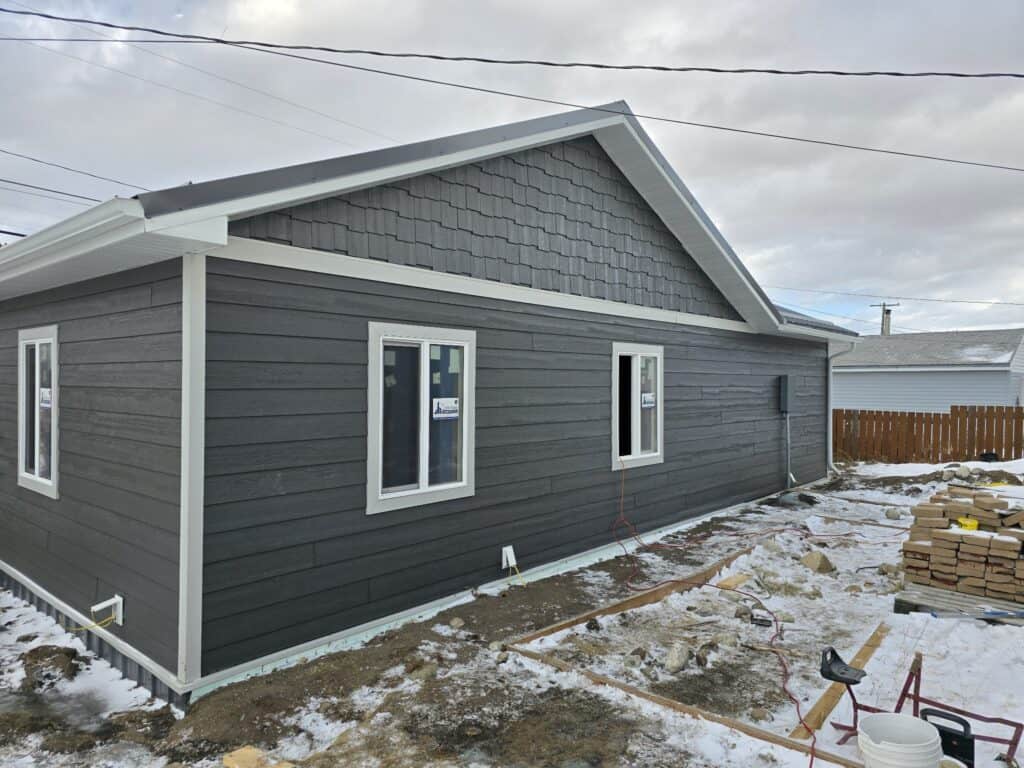 Modern Interior Wall New gray house exterior with siding and windows, under construction in winter.