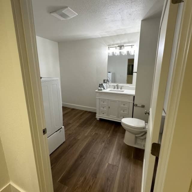 Bathroom Renovation Interior Modern bathroom with white vanity, toilet, and wood flooring.
