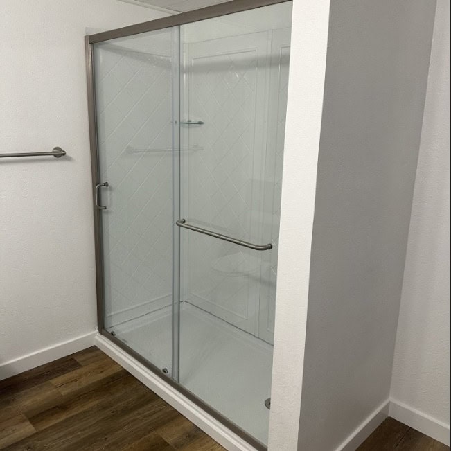 Shower Glass Enclosure Glass shower door with metal frame and handle.