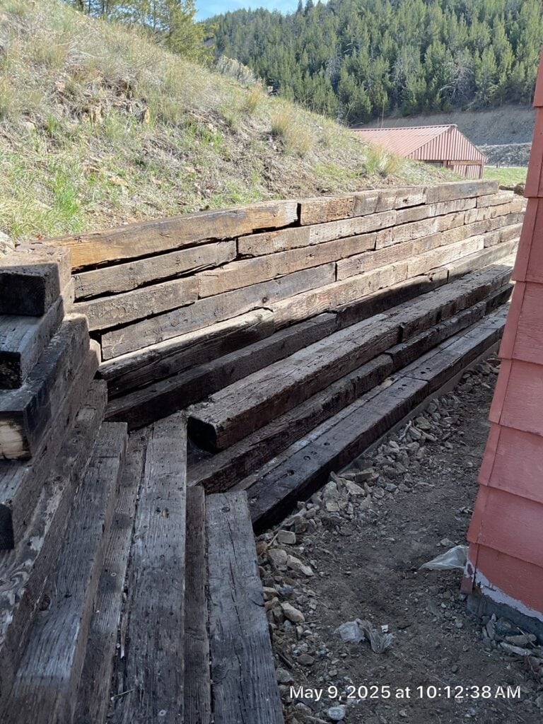 Wooden retaining wall construction for landscape erosion control. Retaining wall made of weathered wood planks for landscape erosion control.