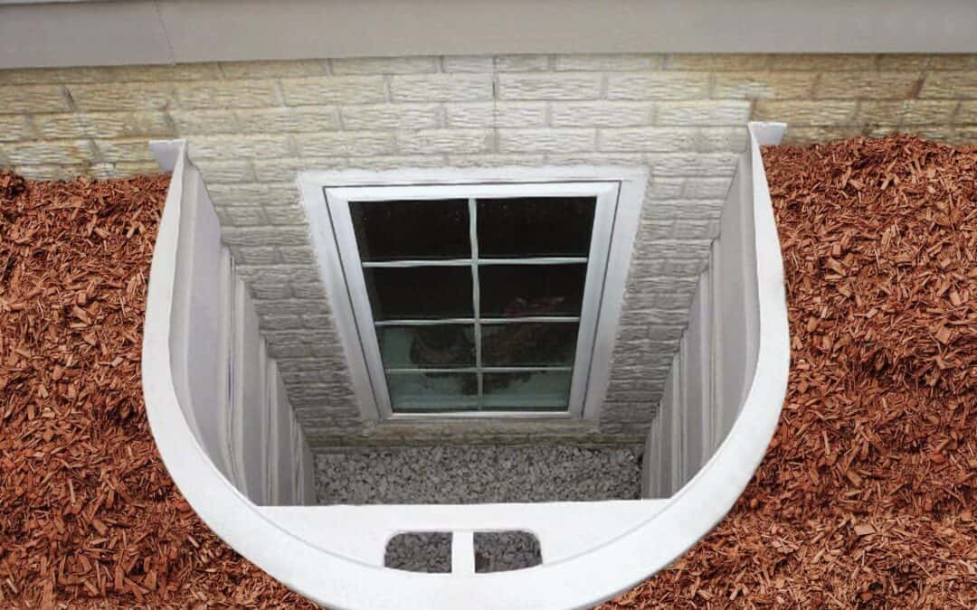 Basement window with white frame installed in brick wall, viewed from above.
