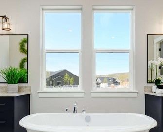 Bathroom window with a scenic outdoor view of houses and hills.