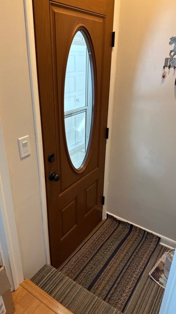 Front Door Installation Wooden front door with oval glass window, installed at residential entryway.