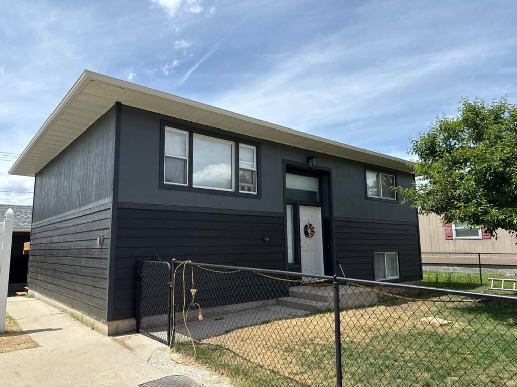 Contemporary black house with large windows and a front yard, showcasing modern residential architec.