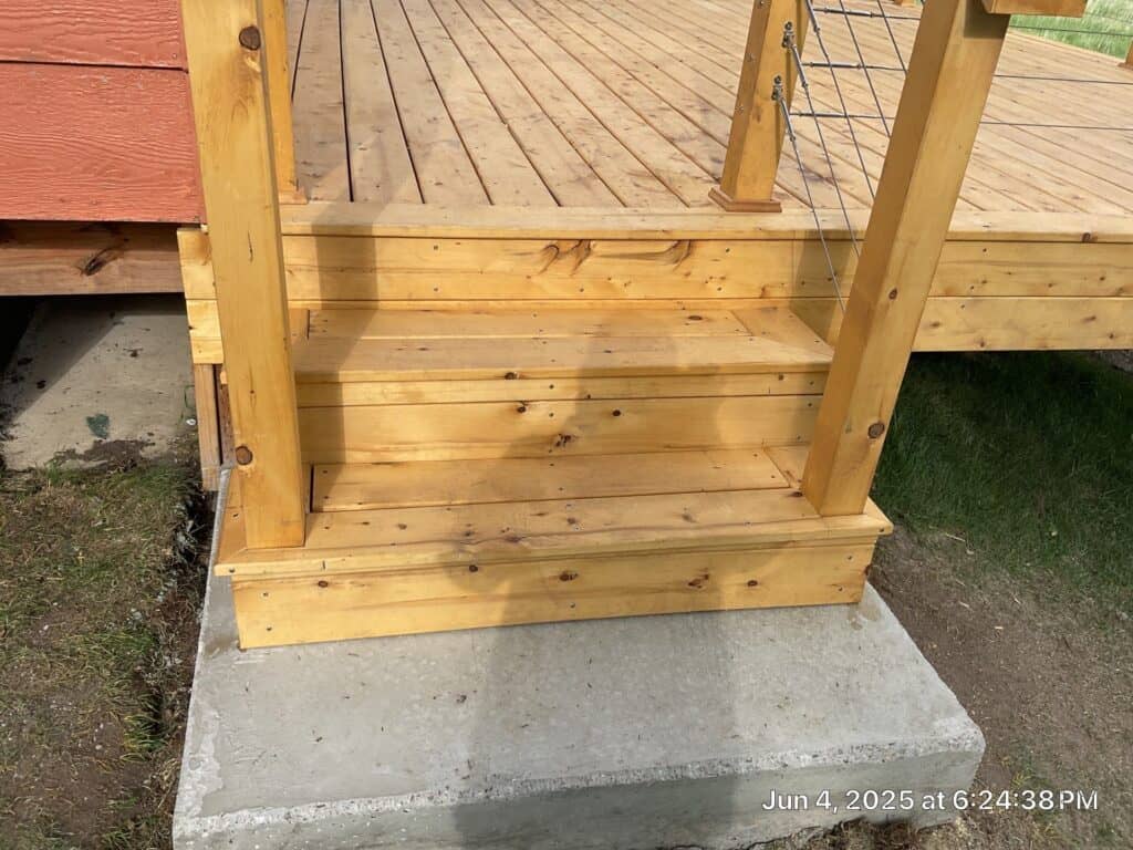 Wooden deck stairs with concrete foundation Wooden deck stairs leading to a raised outdoor deck with concrete footing for stability.