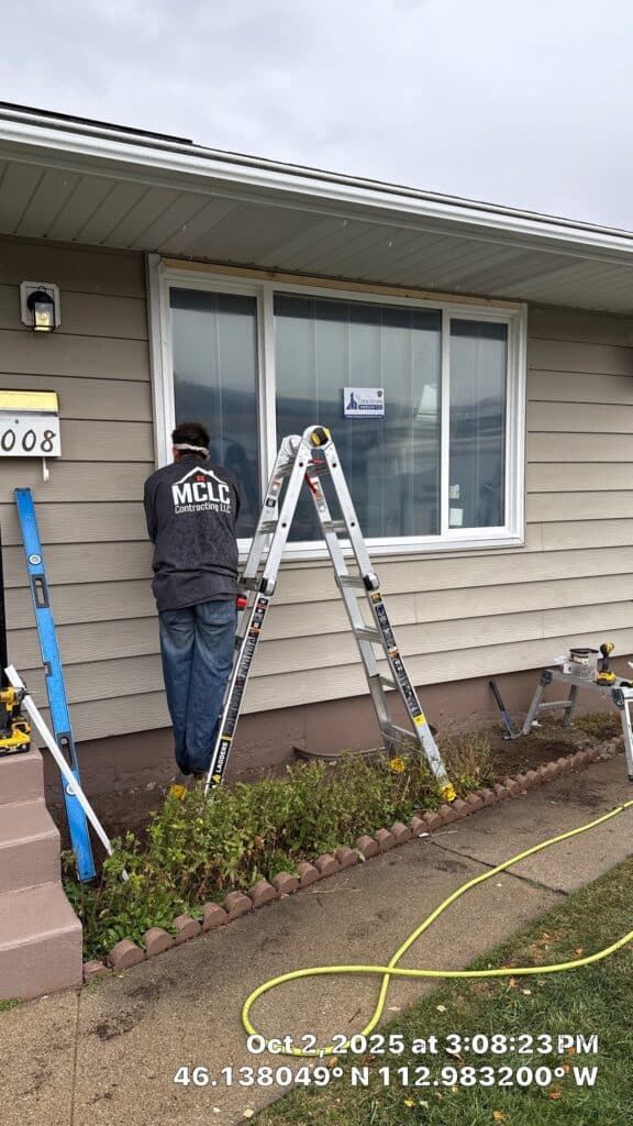 Home Exterior Painting Technician painting the exterior siding of a house with a ladder and painting tools.