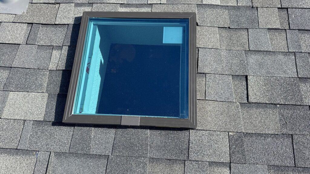 Window Installation Modern square window installed on a shingled roof for natural light and ventilation.