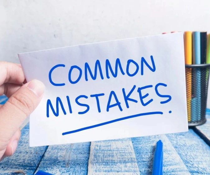 Hand holding a sign that says "Common Mistakes" on a blue wooden surface.