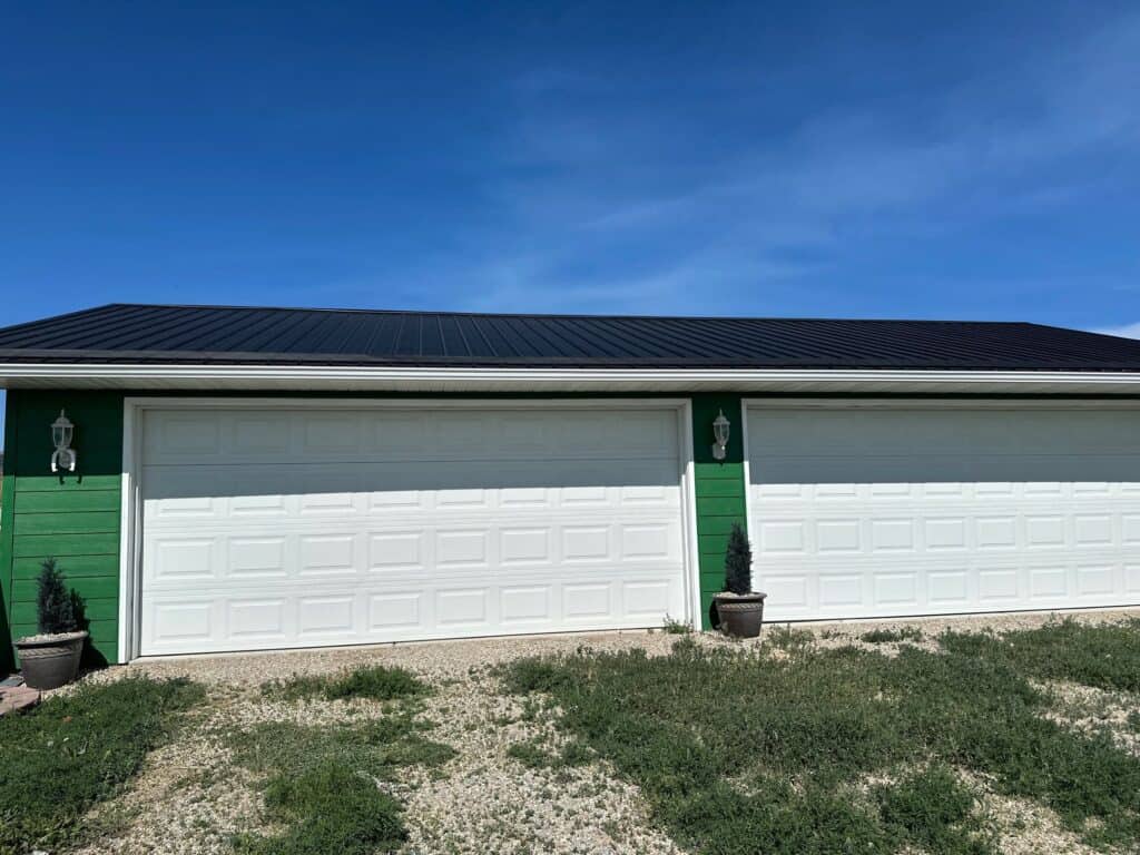 Modern white garage doors with green accents and decorative lighting.