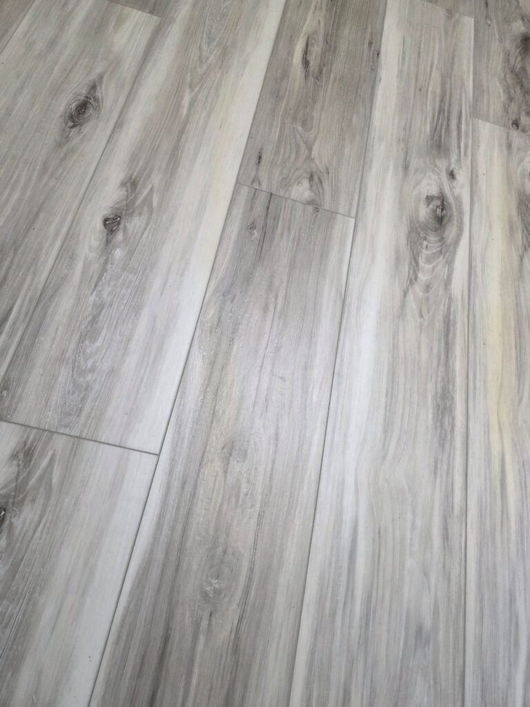 Modern Gray Wood Flooring Light gray wood flooring with natural grain and knot details, ideal for home interiors.