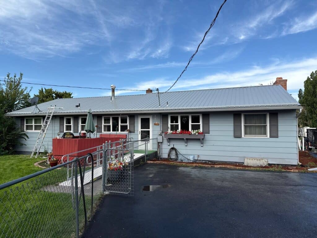 House with new metal roof and siding in a residential yard.