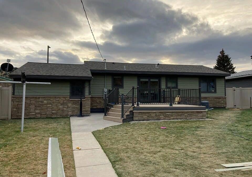 Exterior view of a renovated house with a new porch and landscaping.