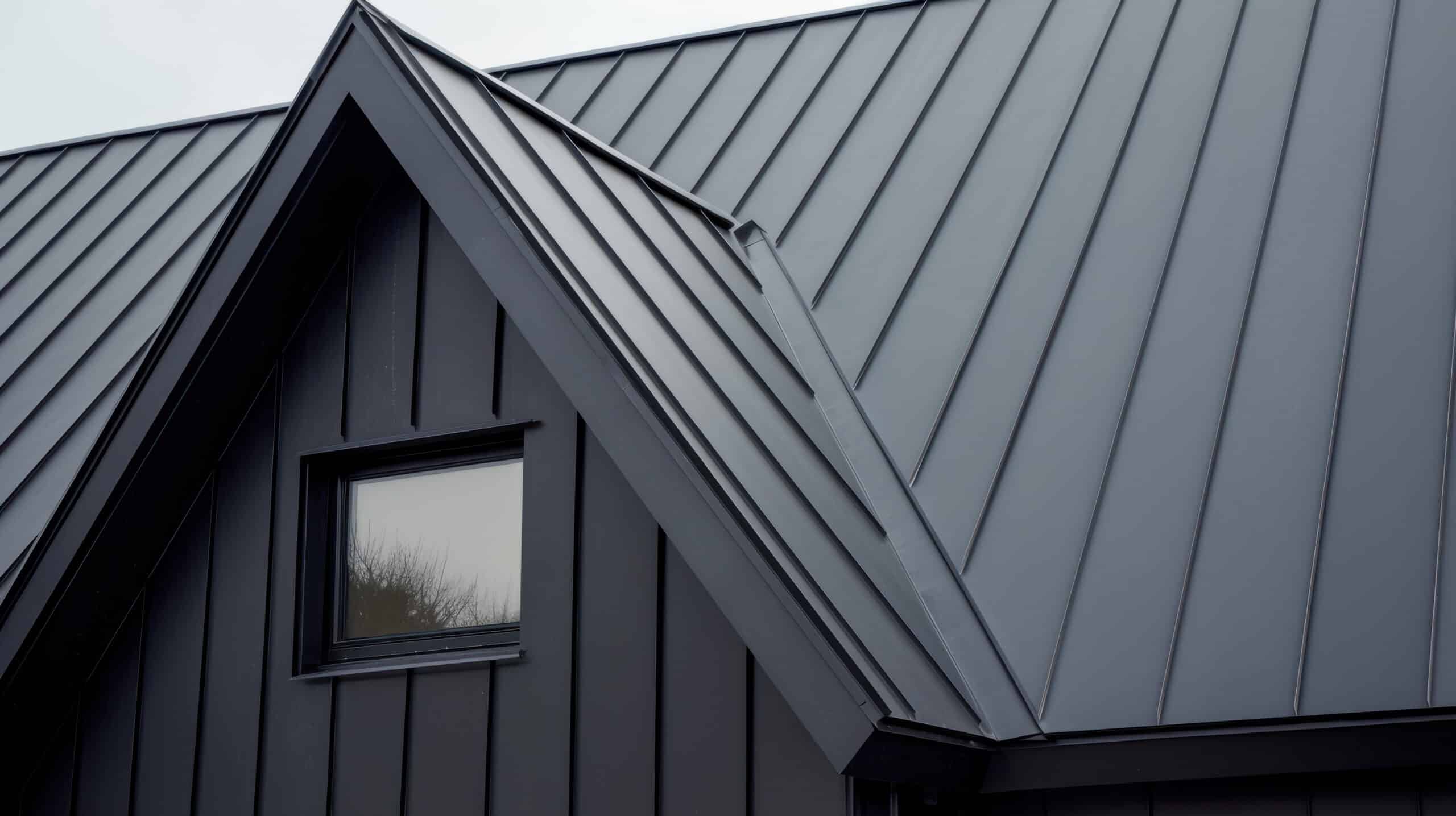 Close-up of a sleek black metal roof with a dormer window.