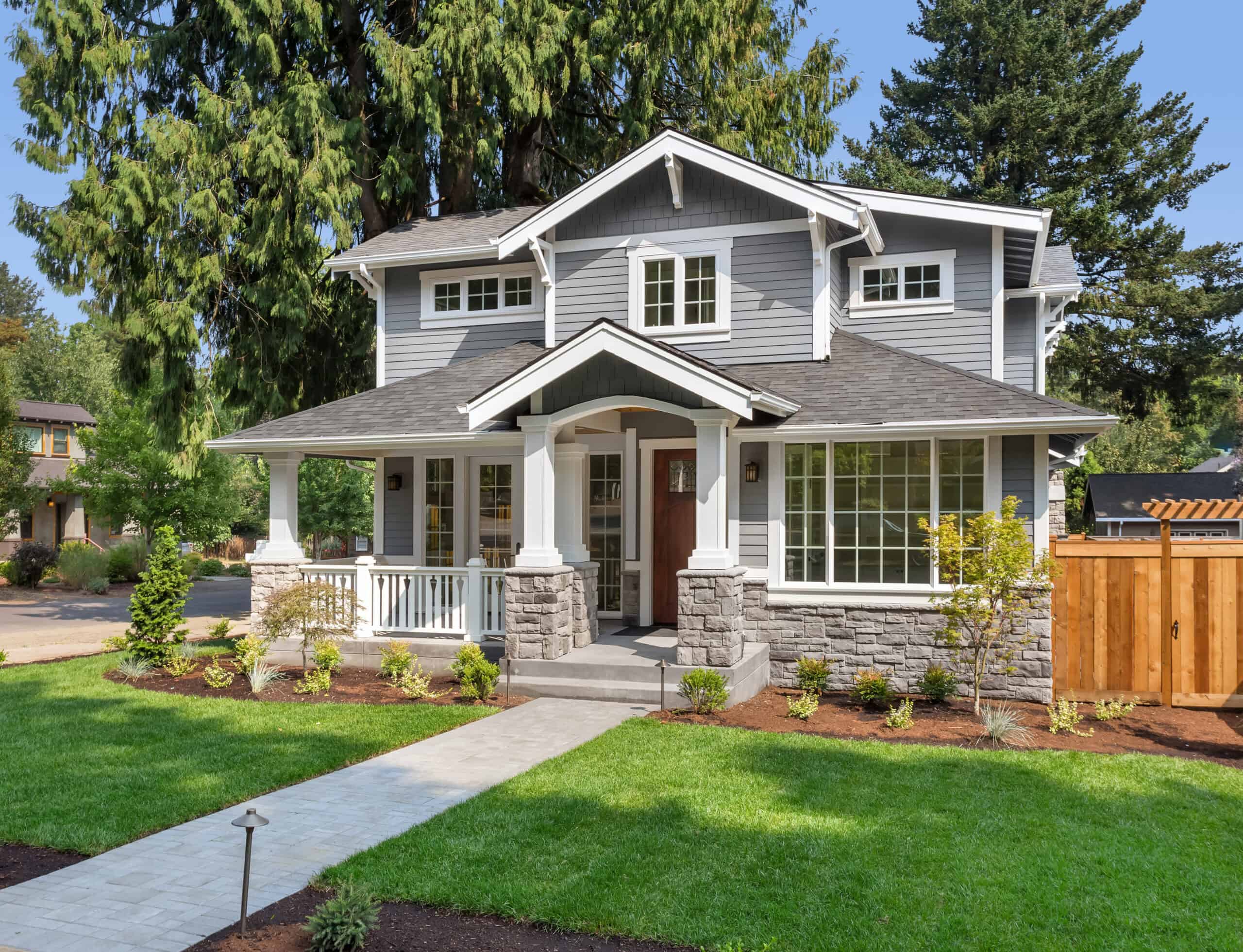 Beautiful modern house with gray siding, large windows, and a landscaped front yard.