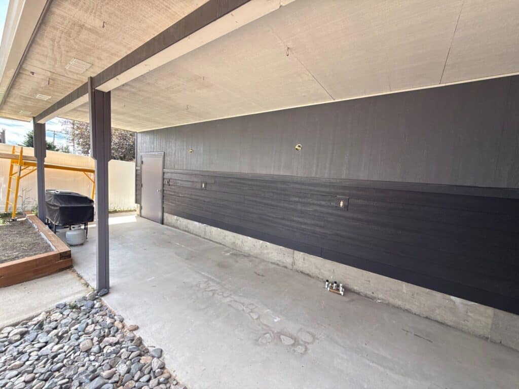 Contemporary building exterior with sleek black siding and concrete foundation.