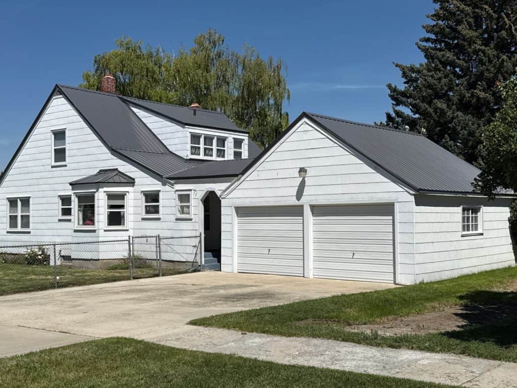 White two-story house with attached garage and well-maintained lawn.