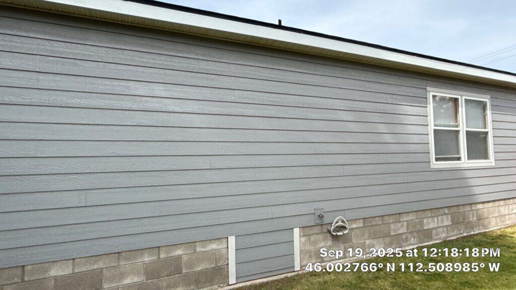 Close-up of light gray siding on residential house with window.