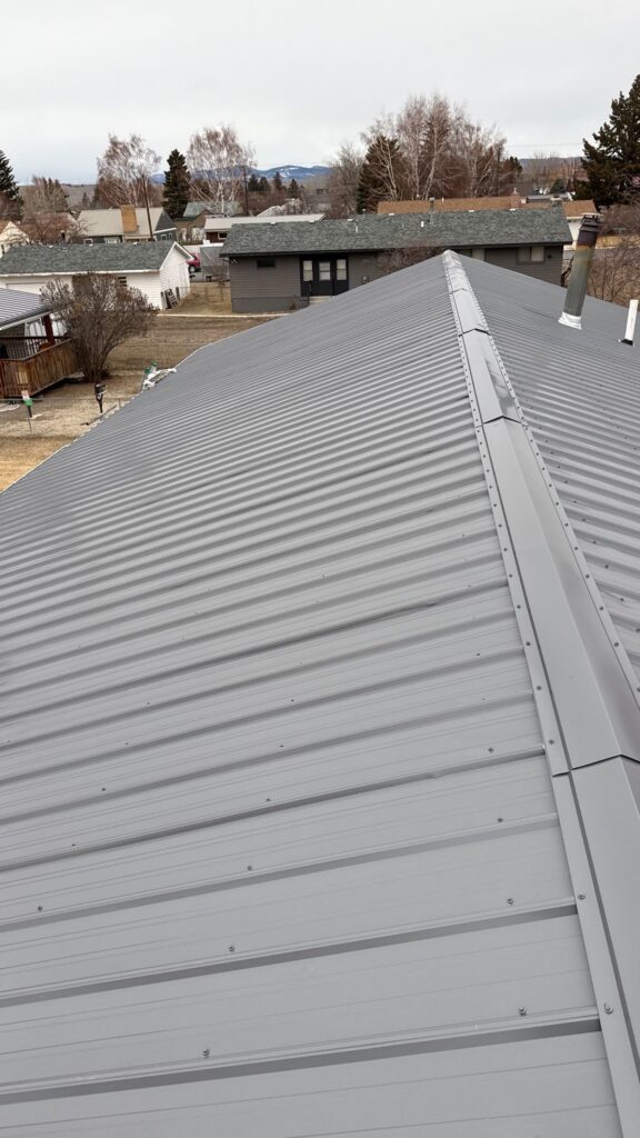 Close-up of a new gray metal roof on a residential home in a suburban neighborhood.