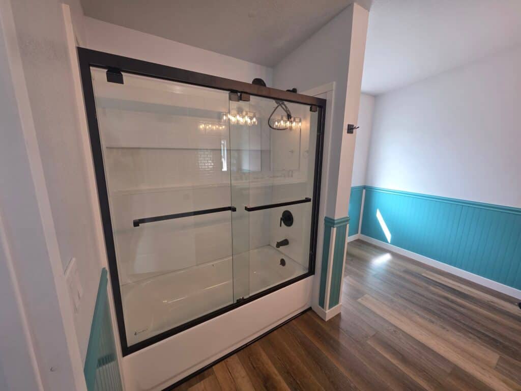 Glass shower enclosure with black frame in a modern bathroom setting.